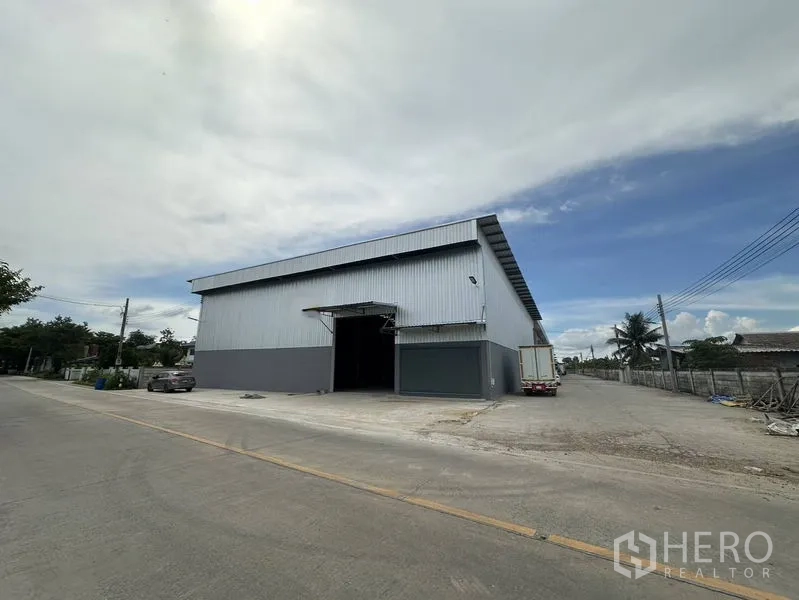 Warehouse for rent in Sai Noi, Nonthaburi - Corner view of large warehouse on wide concrete road with truck access in Sai Noi, Nonthaburi.