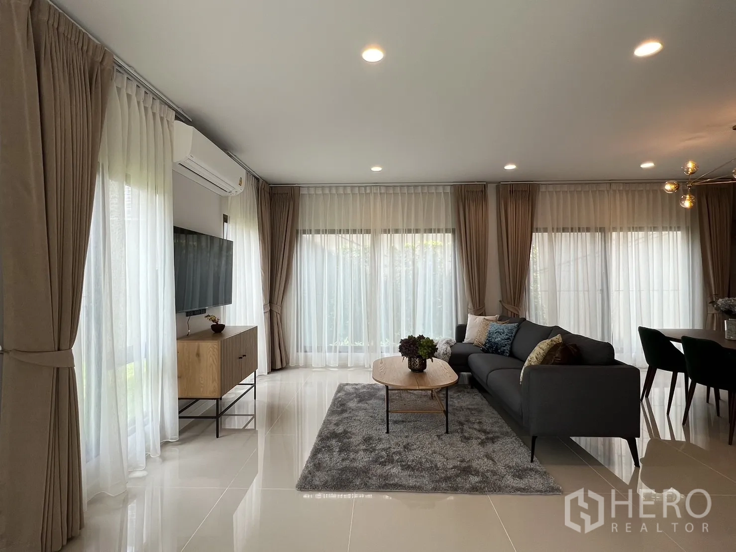 Detached House for rent in Bang Kapi, Bangkok - Bright living room with large windows, sofa and TV, adjoining dining area.