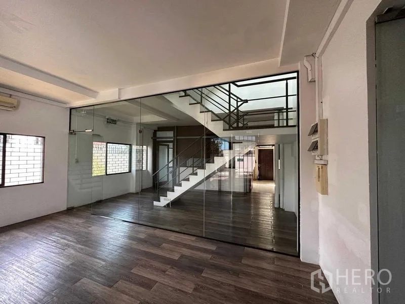 Warehouse for rent in Phra Khanong, Bangkok - Office area with floor-to-ceiling glass partition and wood-style flooring.