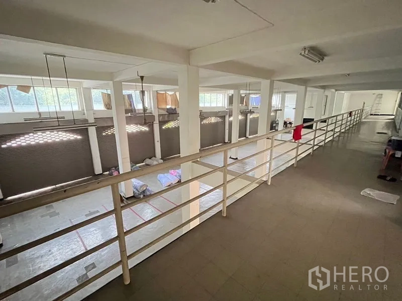 Shophouse for rent in Khlong Toei, Bangkok - Long mezzanine corridor with railing overlooking open floor and shuttered bays below.