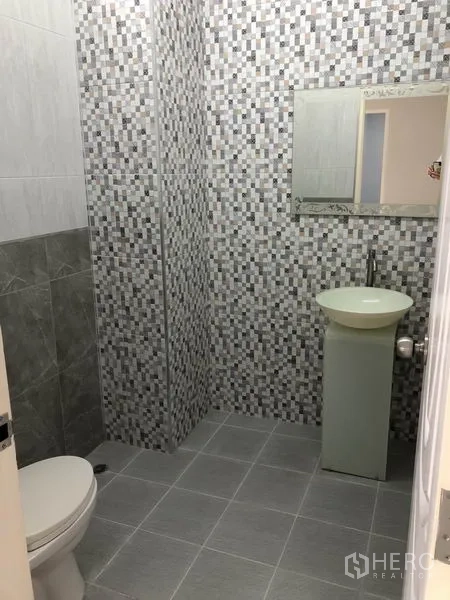 Factory for rent in Bang Len, Nakhon Pathom - Tiled bathroom with toilet, pedestal sink and wall mirror.