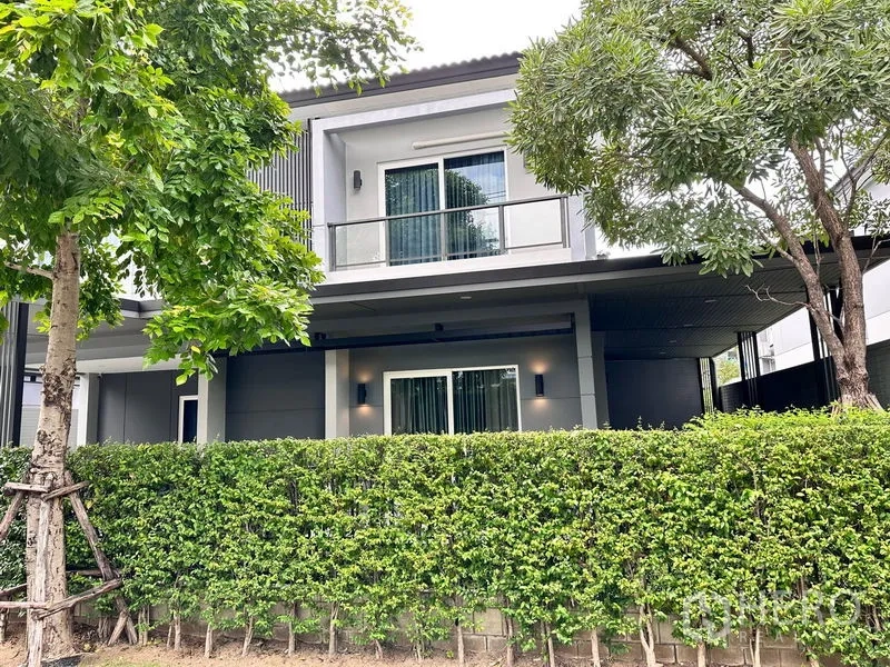 Detached House for sale in Prawet, Bangkok - Rear facade with balcony, sliding doors, hedge and mature trees.