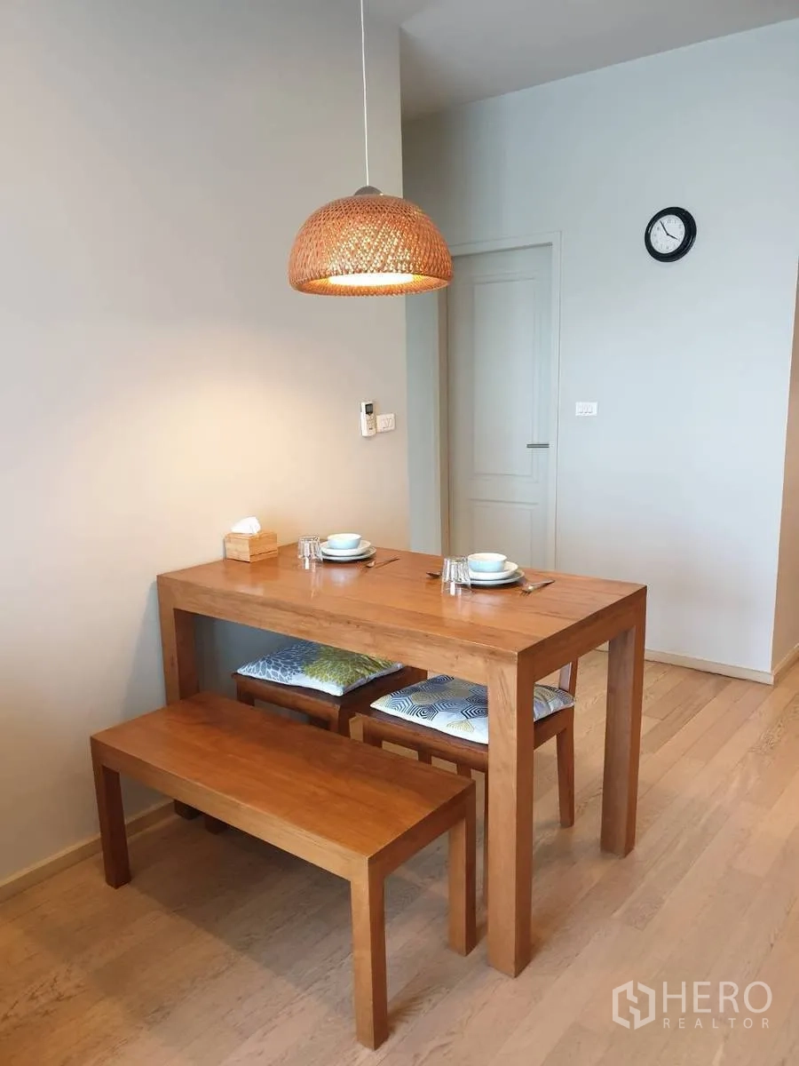 Condominium for rent or sale in Bangkok - Wood dining table with bench seating under a woven pendant light.