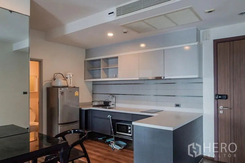Condominium for rent in Khlong Toei, Bangkok - Modern kitchen opposite the entry door with ample countertop and open shelving.