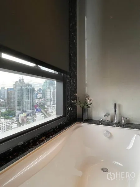 Condominium for rent in Khlong Toei, Bangkok - Bathtub beside a window with panoramic city views.