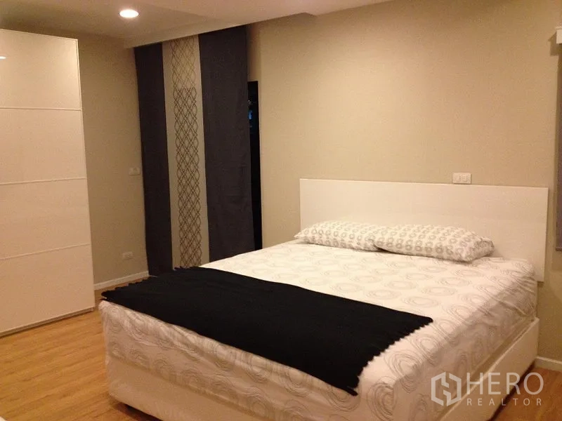 Condominium for rent in Pathum Wan, Bangkok - Bright bedroom with white bed, wardrobe and neutral walls.