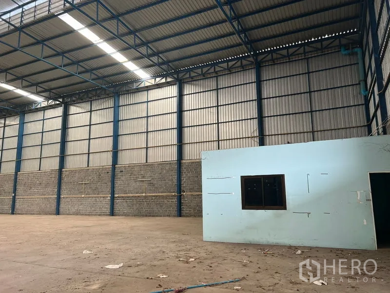 Warehouse for rent in Lat Krabang, Bangkok - Warehouse hall with tall metal walls and a small internal office under the high ceiling.