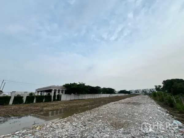 地 出租在Lat Krabang, Bangkok - 地块内抬高的碎石路面，旁有排水与白色围墙，环境安静。
