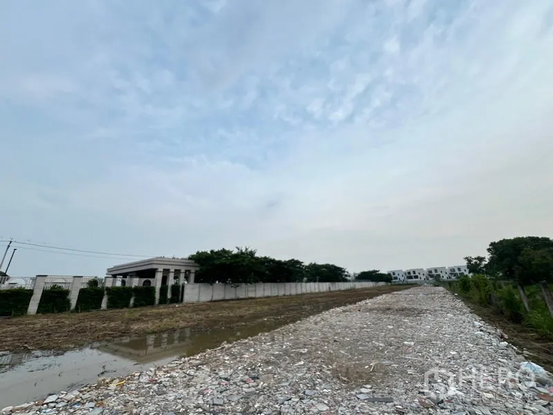 地 出租在Lat Krabang, Bangkok - 地块内抬高的碎石路面，旁有排水与白色围墙，环境安静。
