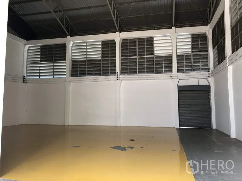 Factory for rent in Lam Luk Ka, Pathum Thani - Production area with ventilation louvres and roller shutter door over yellow epoxy flooring.