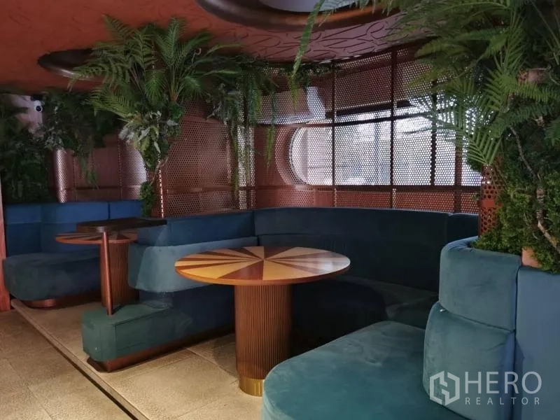 Retail Space for rent - Private booth zone with teal sofas, round inlay tables, and indoor plants.