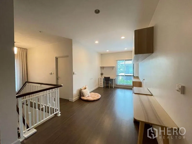 Detached House for sale in Pak Kret, Nonthaburi - Bright upstairs family area with wood flooring, a window-side desk and white stair railing.