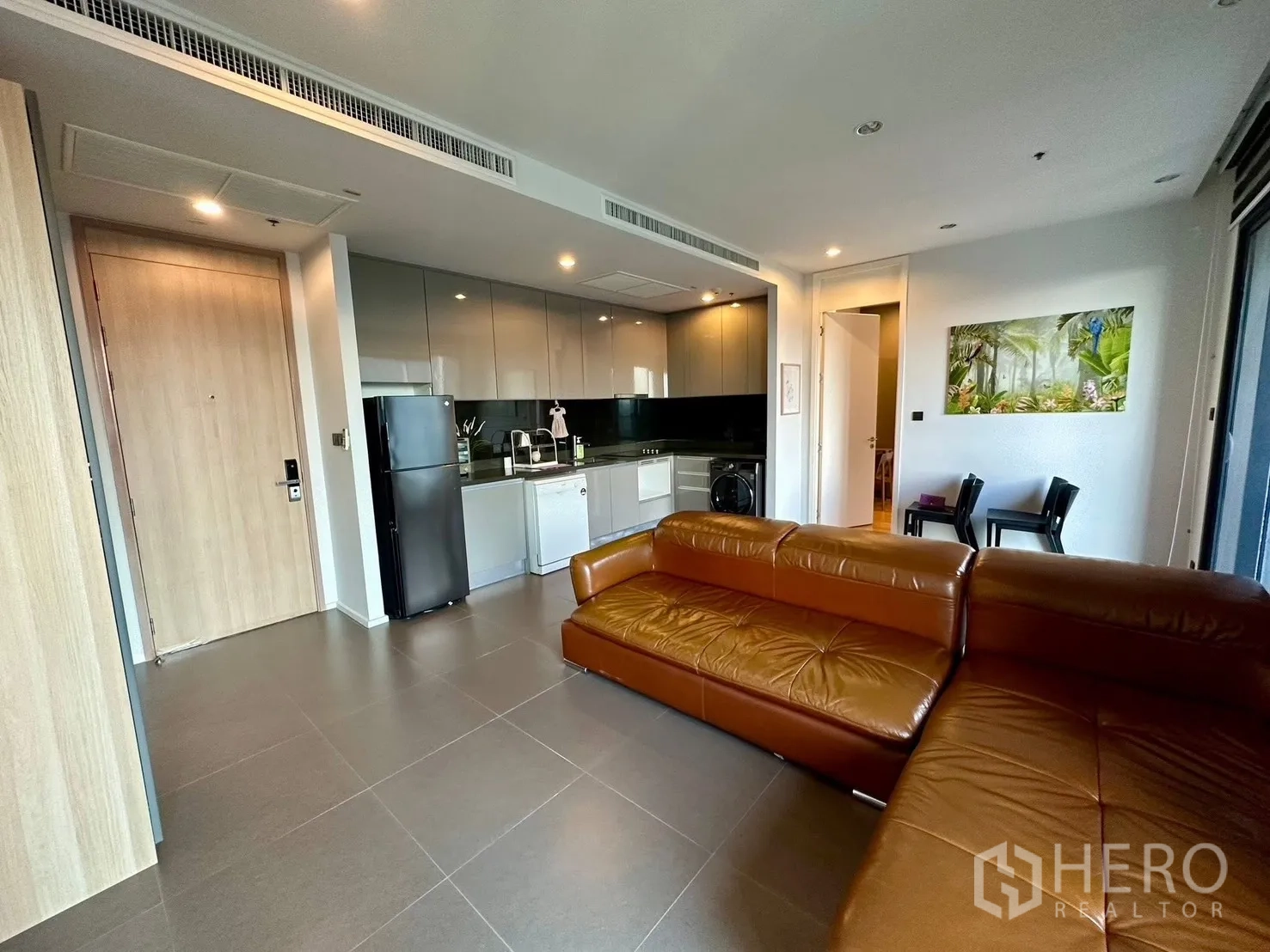 Condominium for rent or sale in Chatuchak, Bangkok - Open-plan kitchen and living space with entry door and sofa.