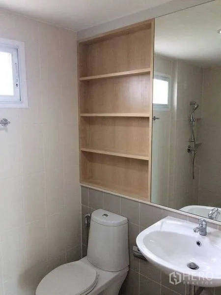 Townhouse for sale in Suan Luang, Bangkok - Clean tiled bathroom with shelving, large mirror, sink, toilet and shower.