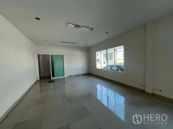 Warehouse for rent in Prawet, Bangkok - Bright tiled office room with large windows and a sliding glass door.