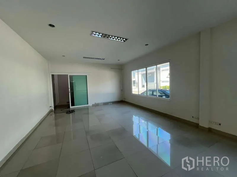 Warehouse for rent in Prawet, Bangkok - Bright tiled office room with large windows and a sliding glass door.
