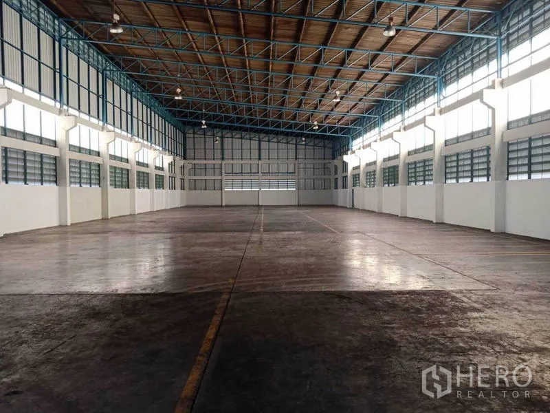 Factory for rent in Samut Prakan - Symmetrical warehouse-style interior with high-bay lighting and durable concrete slab flooring.