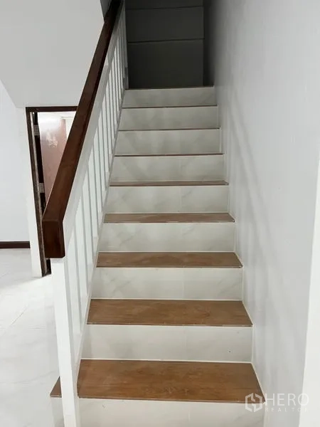 Townhouse for rent in Din Daeng, Bangkok - Straight staircase with tiled steps and a wooden handrail leading to upper floor.