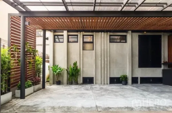 Townhouse for rent in Khlong Toei, Bangkok - Covered carport with wood slat canopy, concrete walls and potted greenery.