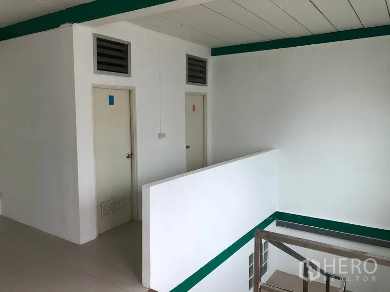 Factory for rent in Lam Luk Ka, Pathum Thani - Upper level corridor with restrooms and stair access inside the factory office block.