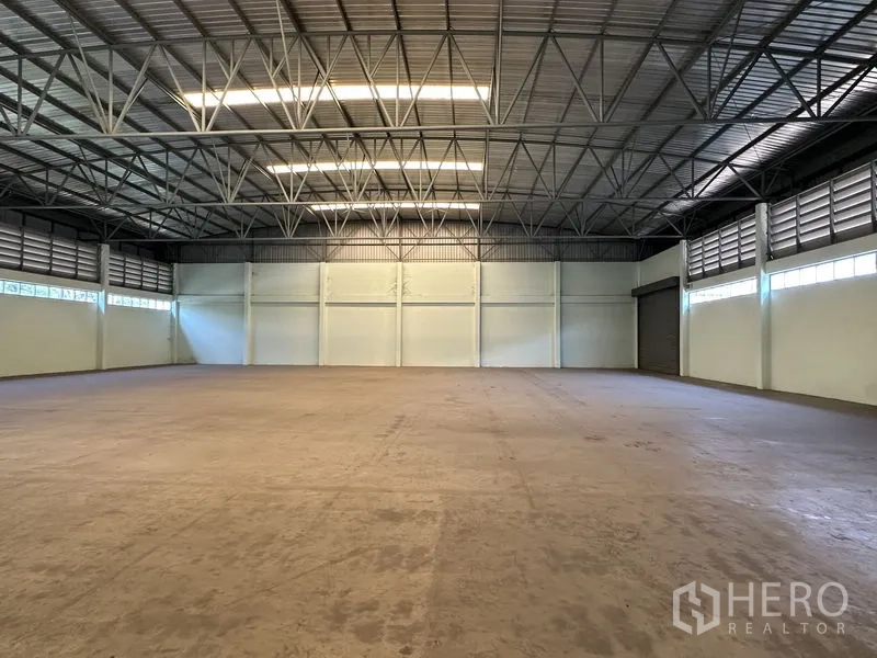 Factory for rent in Chon Buri - Spacious production hall with high steel truss roof, ventilated clerestory windows and concrete floor.