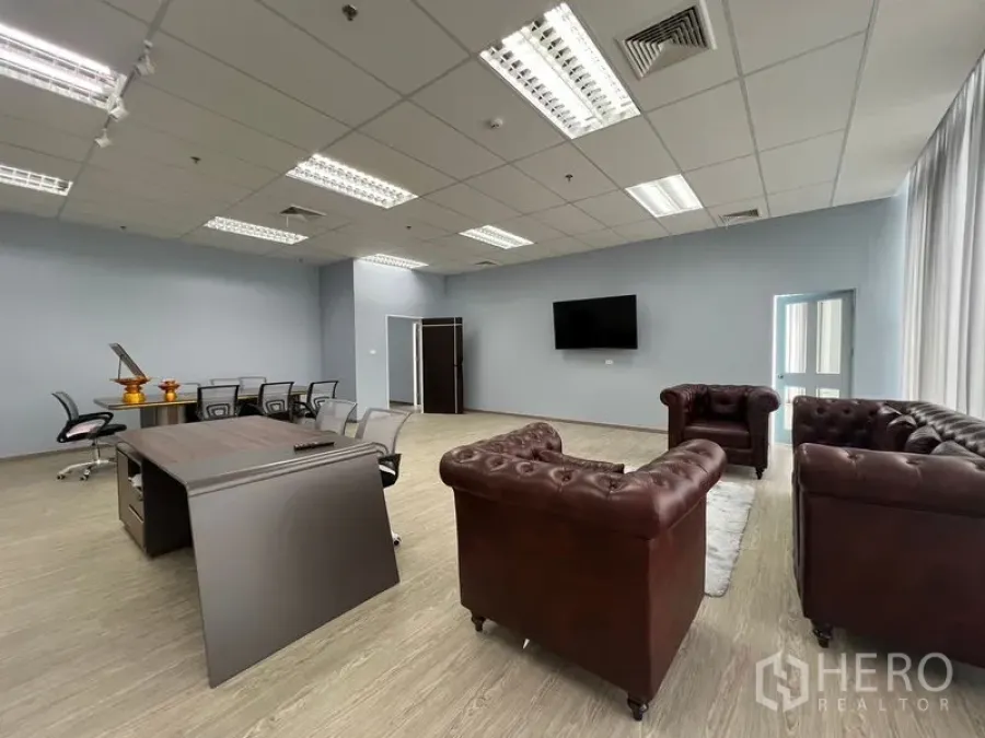Office Space for rent - Executive area featuring brown leather sofas, meeting table and a wall-mounted TV in a modern office.