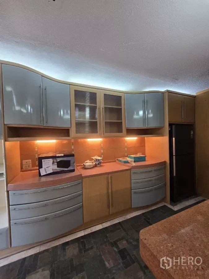 Condominium for rent in Pathum Wan, Bangkok - Kitchen cabinetry with under‑cabinet lighting, stone countertop and tall refrigerator.