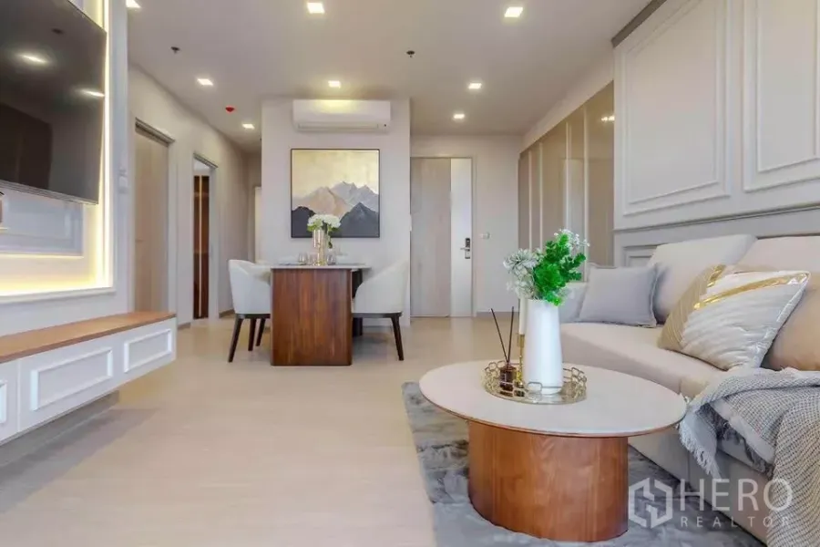 Condominium for rent in Huai Khwang, Bangkok - Bright living room with sofa, wall moulding, TV feature wall and round coffee table.