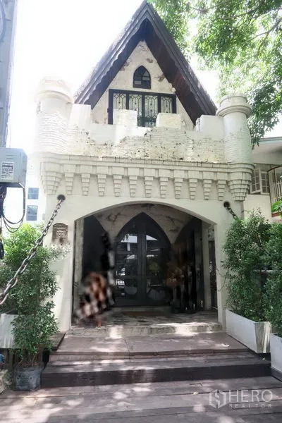 Retail Space for rent in Watthana, Bangkok - Castle-inspired retail building facade with steep gable roof and arched entry shaded by trees in Thonglor, Bangkok.