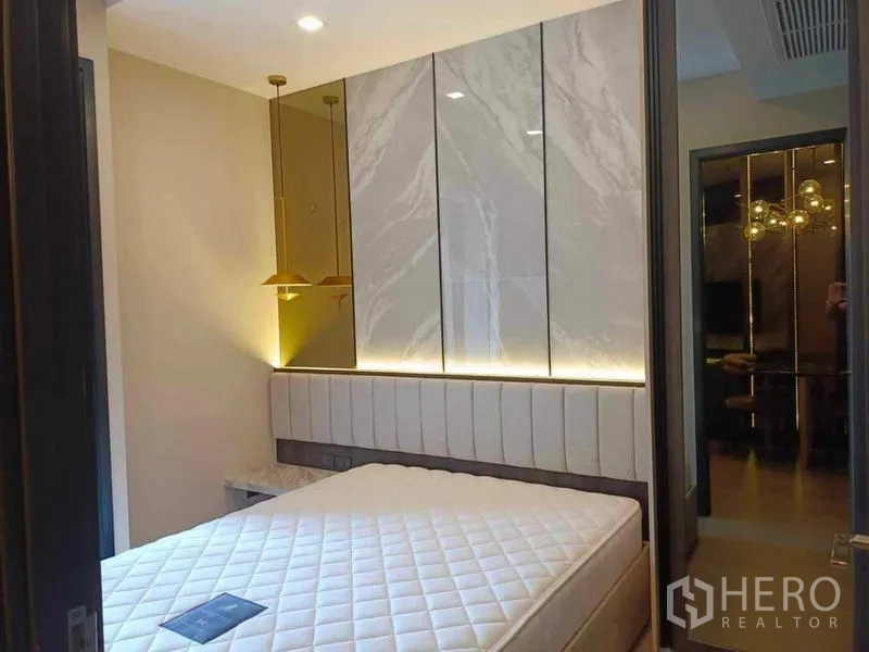 Condominium for rent in Watthana, Bangkok - Bedroom with upholstered headboard, marble accent wall and bedside pendant lights.