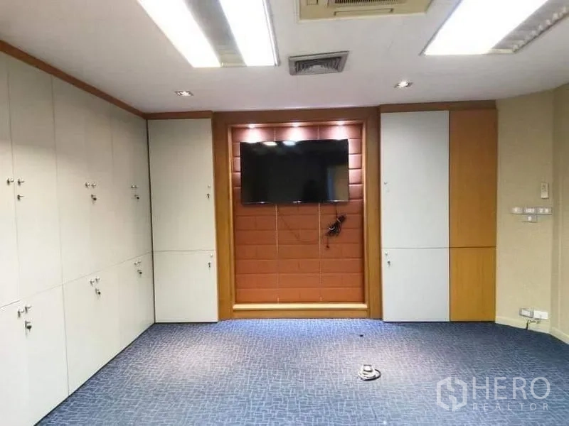 Office Space for rent - Media or conference room with wall-mounted TV, accent wall and ample storage cabinets.