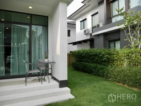Detached House for rent in Bang Kapi, Bangkok - Small patio with sliding glass doors opening to a lawn beside neighboring modern homes.