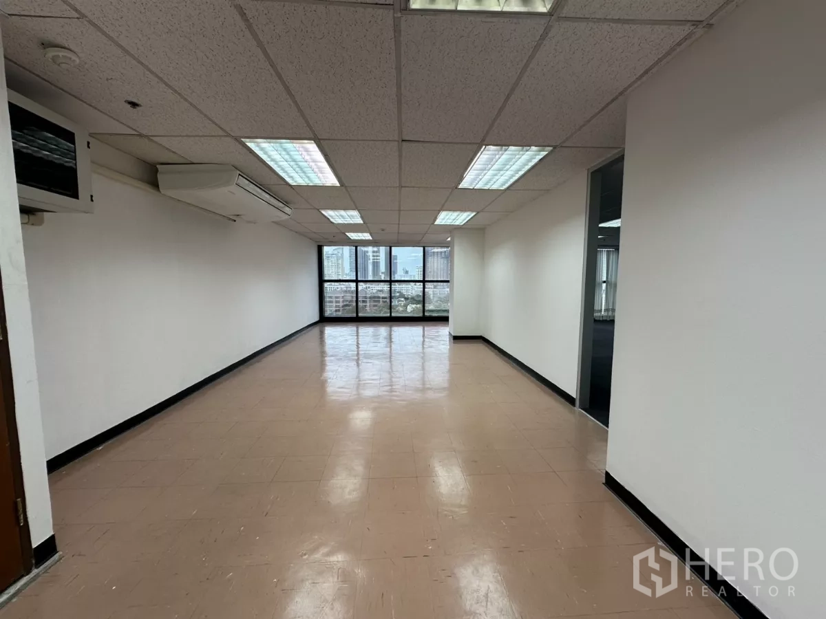 Office Space for rent in Watthana, Bangkok - Long tiled ancillary room with split-type AC and a window facing the city skyline.