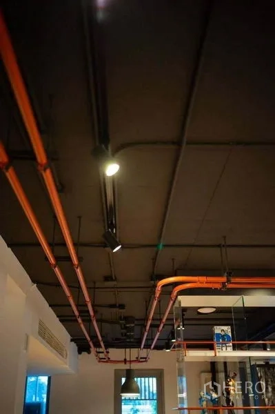Office Space for rent in Khlong Toei, Bangkok - Close-up of exposed ceiling with orange conduits and track lights for an industrial look.