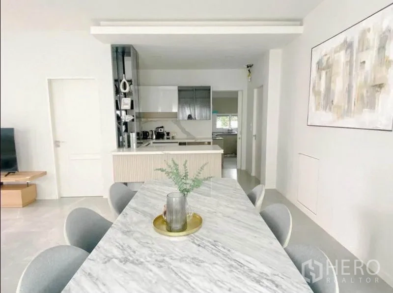 Detached House for rent in Prawet, Bangkok - Dining area with a marble table facing a sleek pantry and built-in cabinetry.