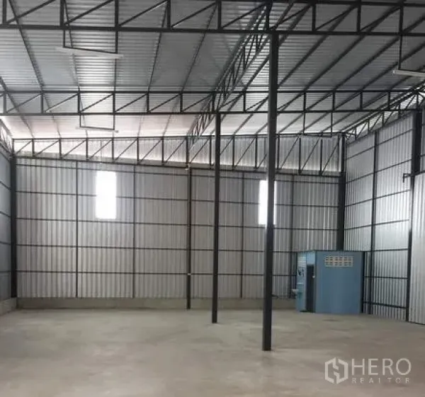 Warehouse for rent in Bueng Kum, Bangkok - Open warehouse floor with steel columns, vented windows, and a small utility room along the wall.