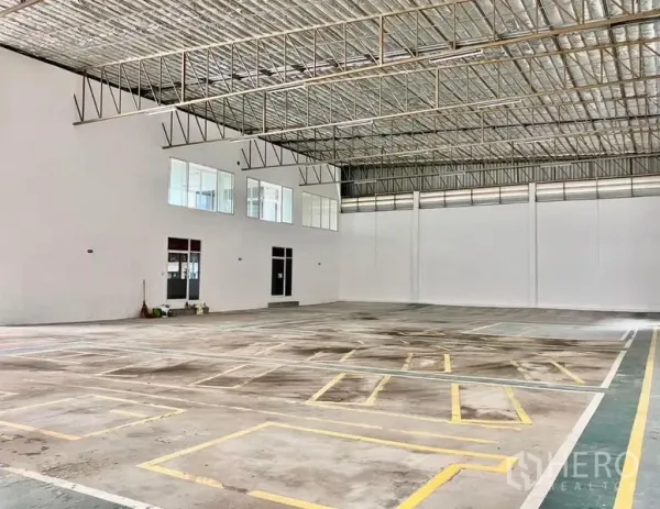 Warehouse for rent in Prawet, Bangkok - Large warehouse interior with high insulated roof, marked loading bays, and mezzanine windows.