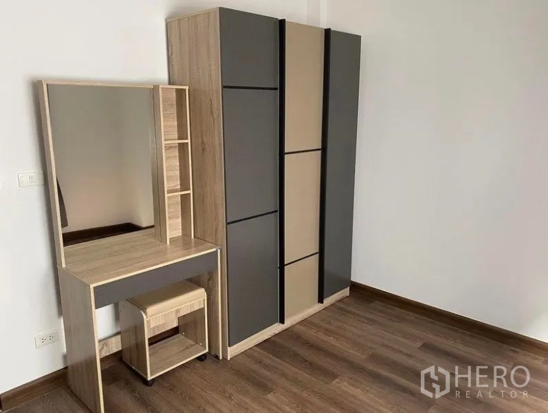Townhouse for rent in Bang Na, Bangkok - Bedroom corner featuring a wardrobe and dressing table set on wood flooring.