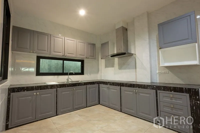 Home Office for rent in Bang Khen, Bangkok - Built-in L-shaped kitchen with gray cabinetry, marble-look countertops and range hood.