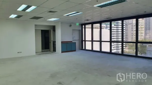 Office Space for rent in Watthana, Bangkok - Open workspace with large windows, a small pantry alcove, and doorway access.