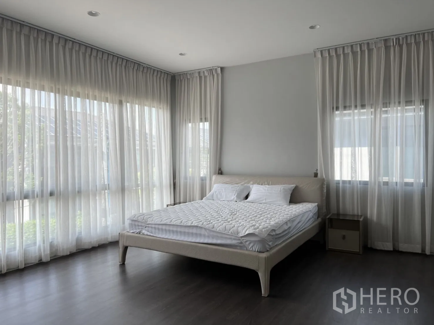 Detached House for rent in Bang Kapi, Bangkok - Corner master bedroom with sheer curtains, large windows, and wood flooring.