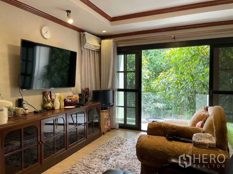 Home Office for rent in Watthana, Bangkok - Living room with sliding glass doors opening to lush greenery outside.