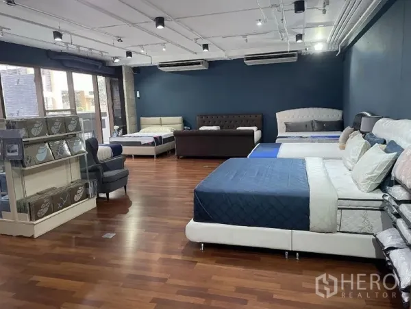 Retail Space for rent - Spacious retail showroom with wooden floors, dark blue feature wall, track lighting, large windows and multiple air-conditioning units.