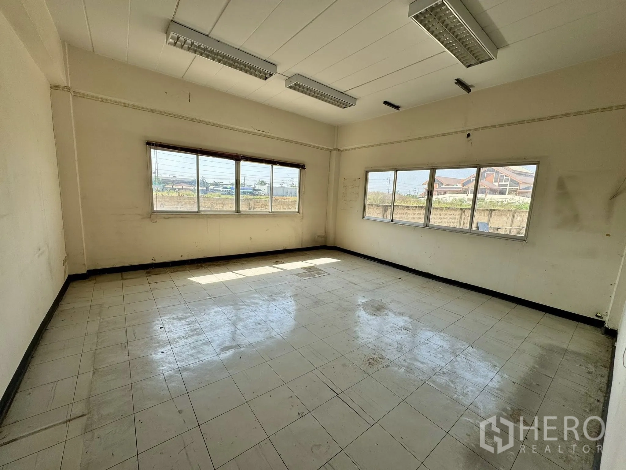 Warehouse for rent in Mueang Samut Sakhon, Samut Sakhon - Sunlit office with windows on two walls and suspended fluorescent lights.