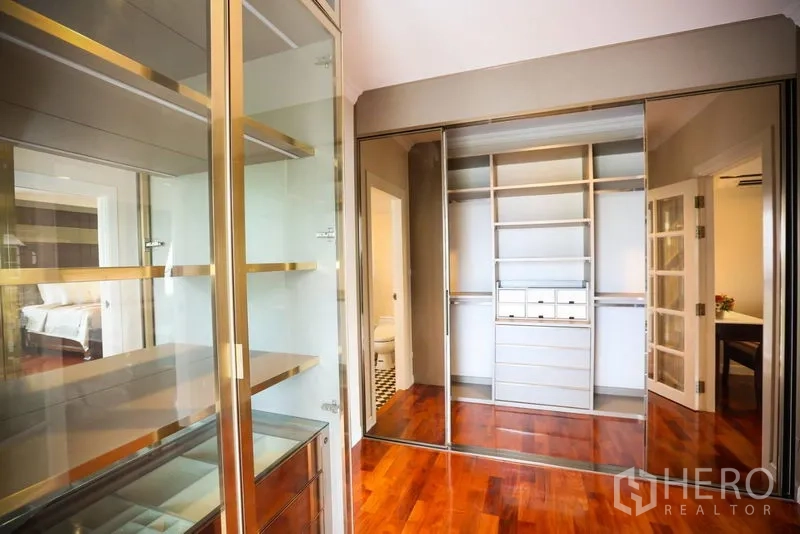 Detached House for rent in Bang Na, Bangkok - Walk-in closet with mirrored sliding doors and glass display cabinetry.