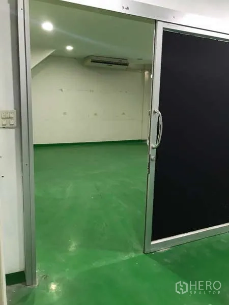 Factory for rent in Bang Phli, Samut Prakan - Sliding door entry into a bright workroom with green flooring.