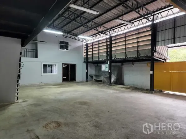 Warehouse for rent in Chatuchak, Bangkok - Spacious loading area with utility sink, electrical panel and a partially open yellow gate.