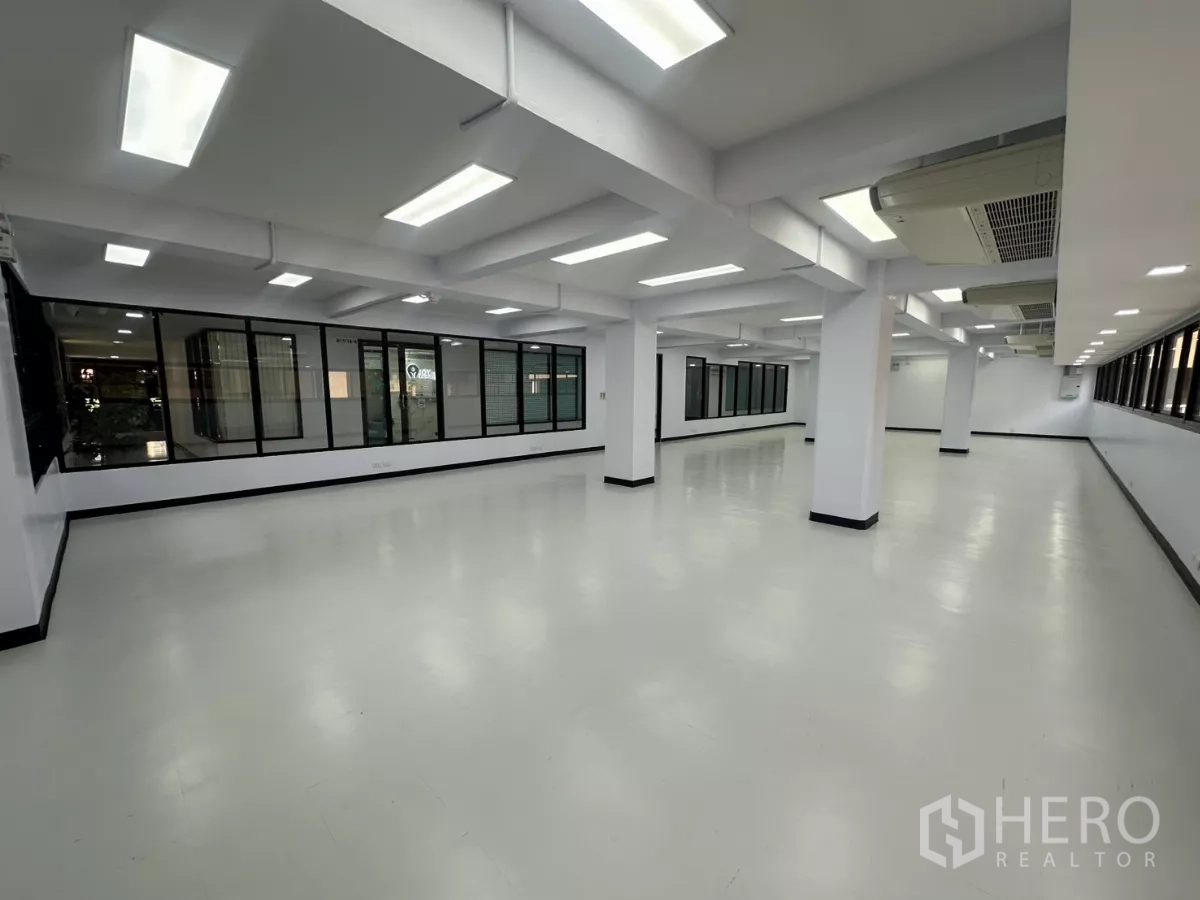 Office Space for rent - Large office area with multiple columns, glass partition wall and evenly spaced ceiling lights.