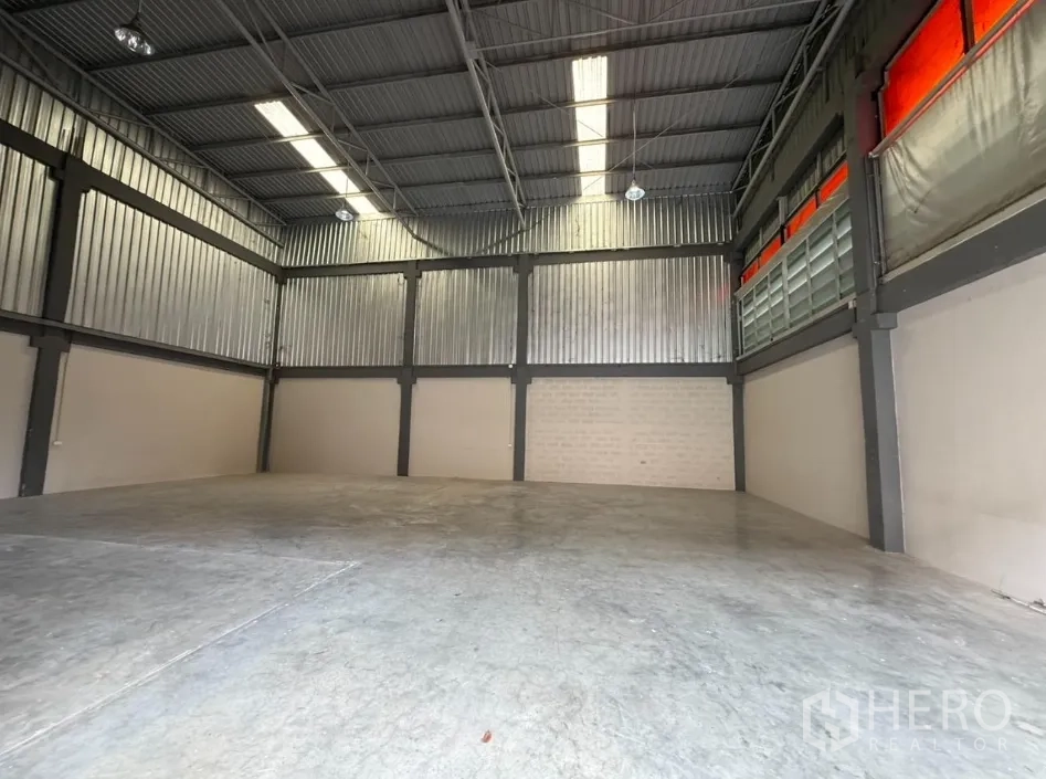 Factory for rent in Khlong Luang, Pathum Thani - Wide warehouse space under metal roof with ridge skylights and side louvers.