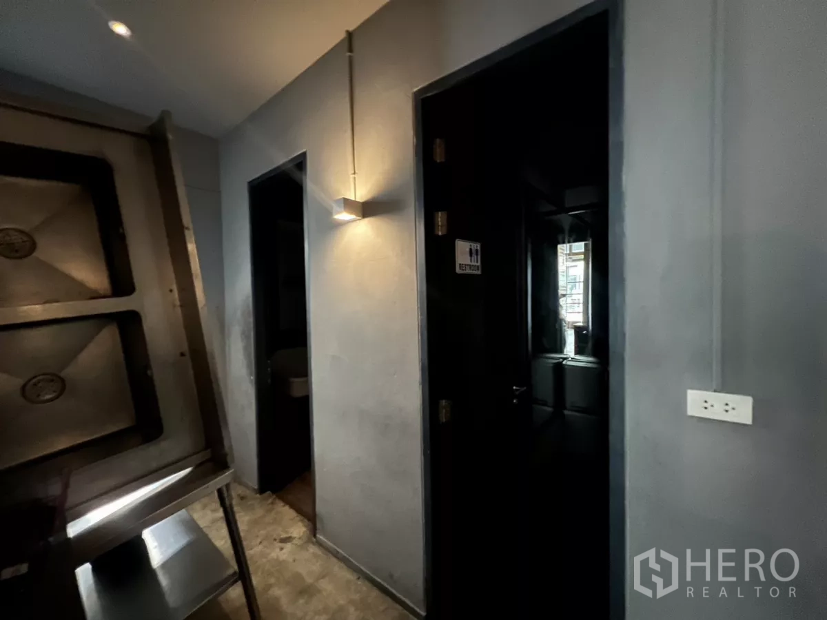Retail Space for rent - Corridor to restrooms with wall sconce and dark doors.